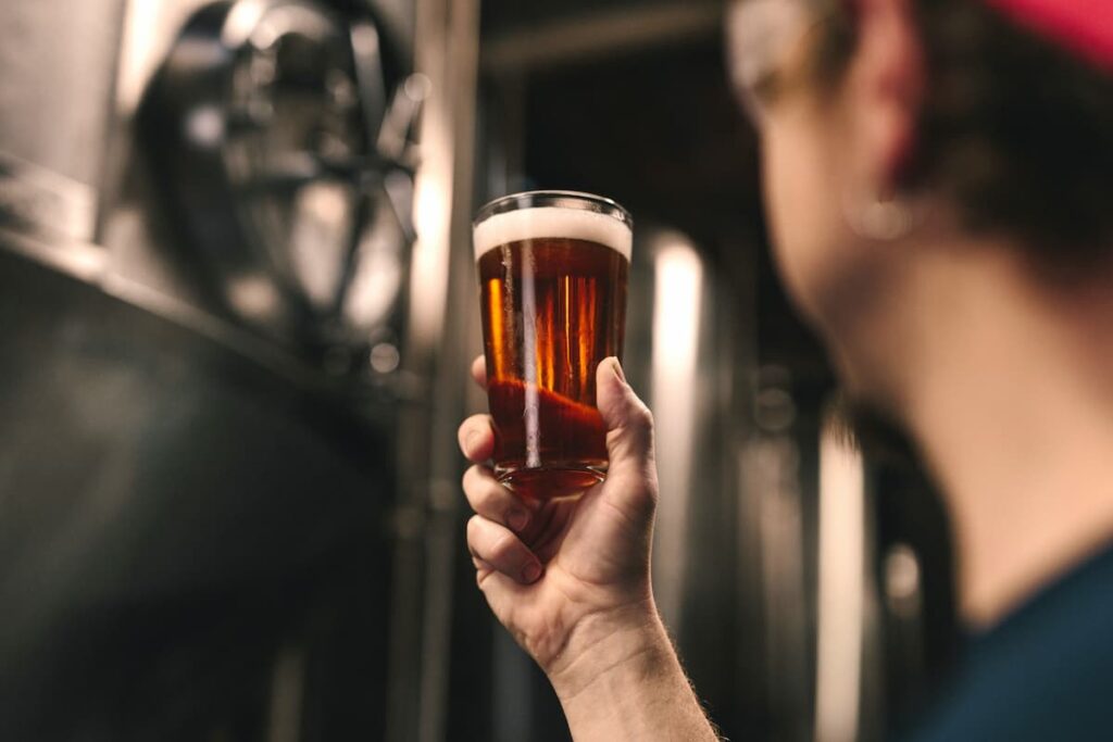 Um homem segurando um copo de cerveja em sua mão 