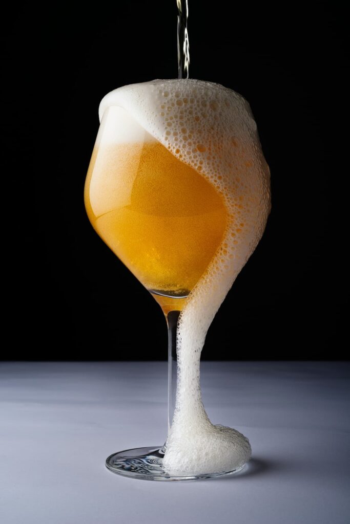 Uma taça de cerveja com a espuma escorrendo pelo vidro da taça 