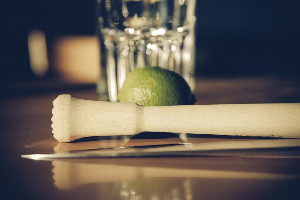 Um copo para fazer cachaça, com limão e um espremedor de madeira