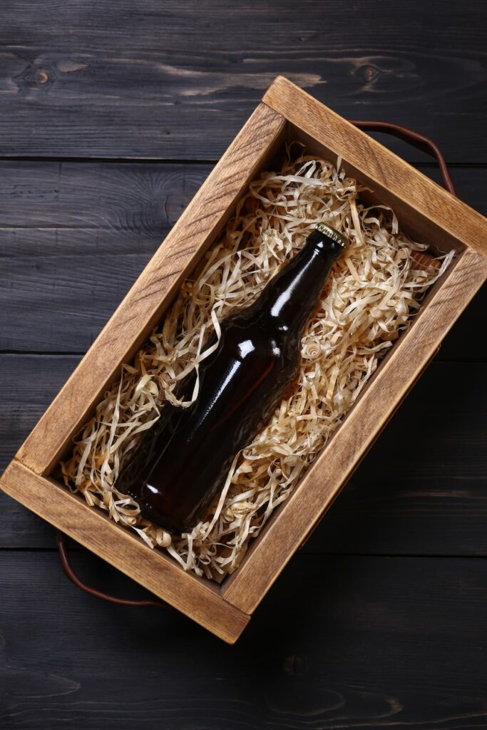Uma caixa de madeira com uma garrafa de cerveja dentro, apoiada em uma mesa 