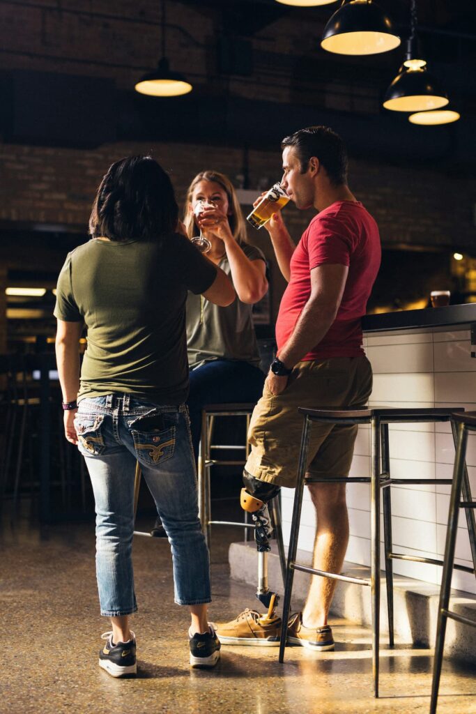 Três amigos em pé, em um bar, tomando cerveja