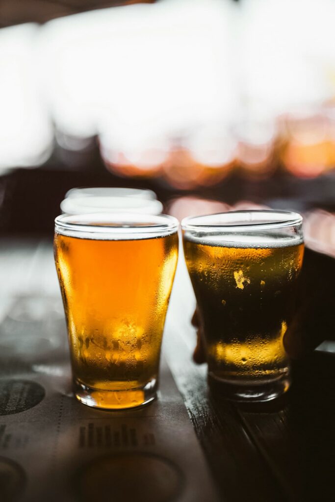 Dois copos de cerveja em uma mesa de madeira de um bar 