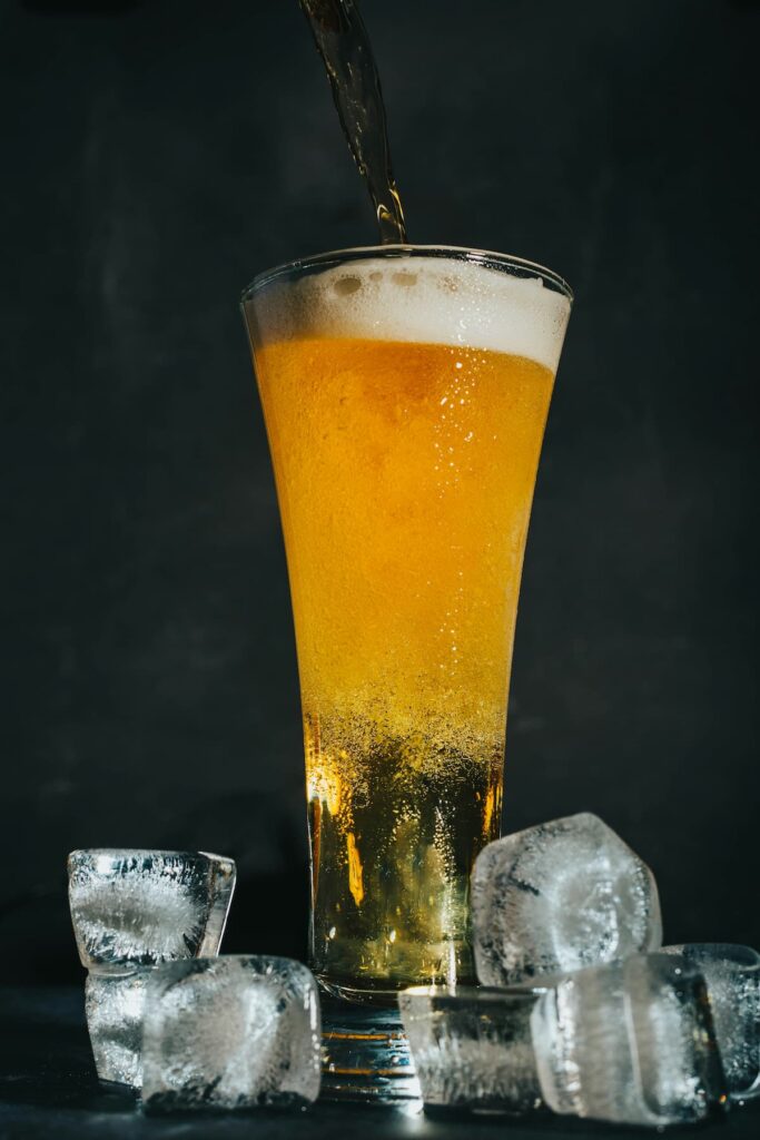 Um copo de cerveja cheio com gelo ao lado 
