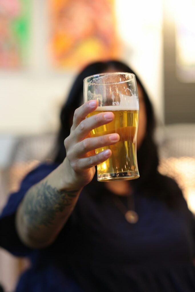 Uma mulher segurando um copo de cerveja
