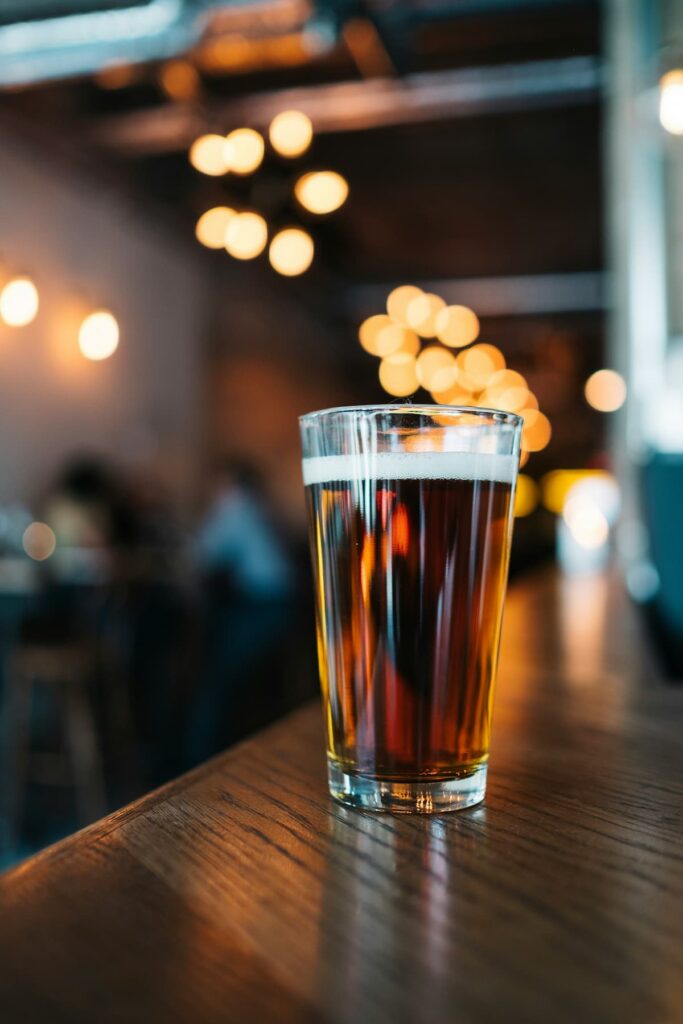 Um copo de cerveja em cima de uma mesa de madeira 