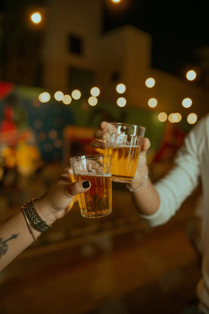 Duas pessoas brindando com um copo de cerveja 