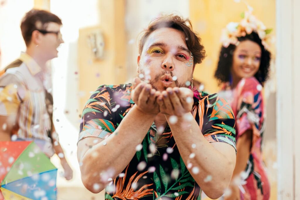 Um homem assoprando confete de carnaval para a foto