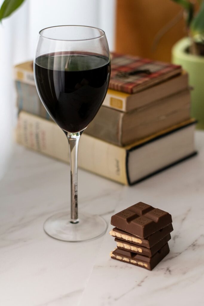 Uma taça de vinho com um pedaço de chocolate ao lado