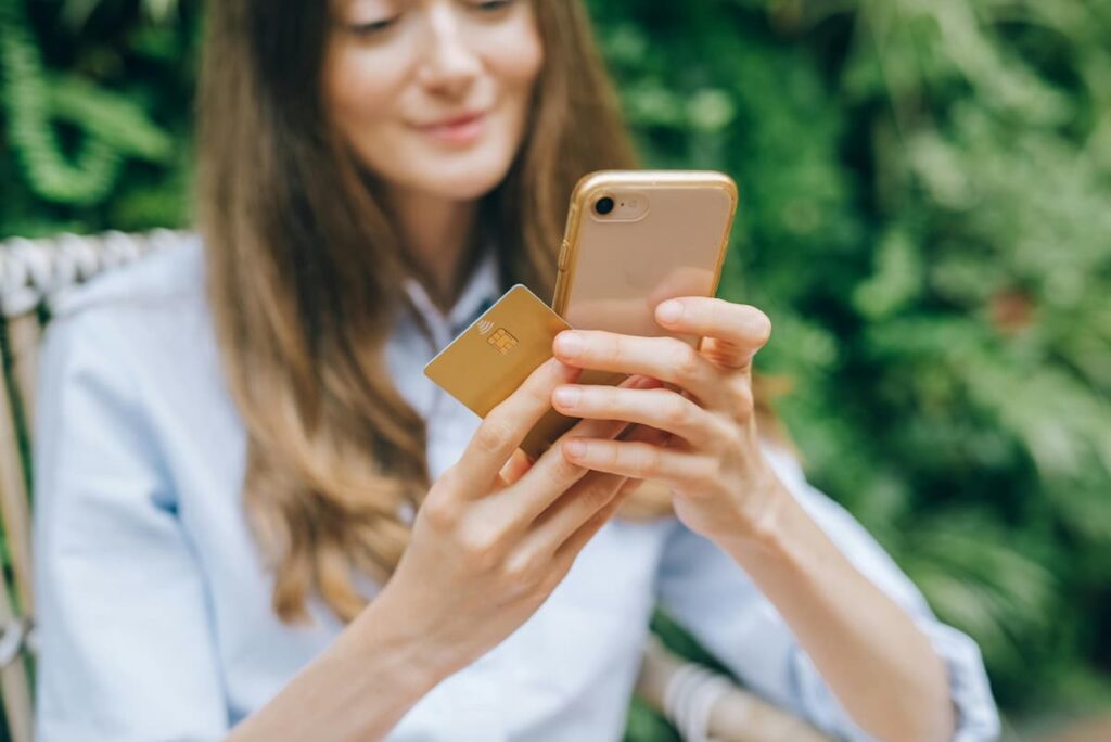 Mulher olhando celular e cartão