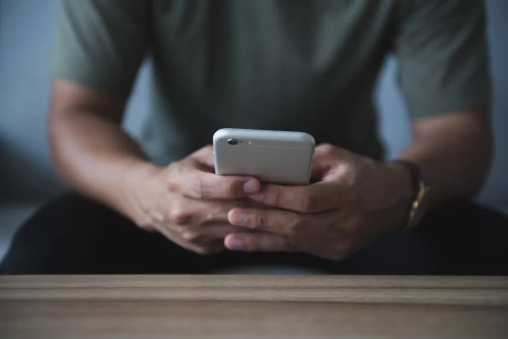 Foto de um homem mexendo no celular